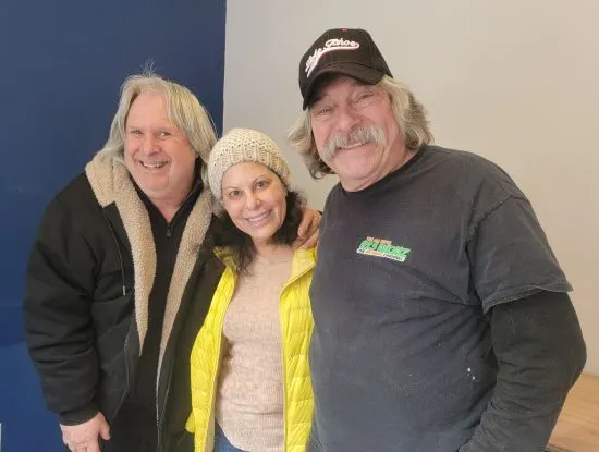 Three people smiling and posing for a photo indoors.